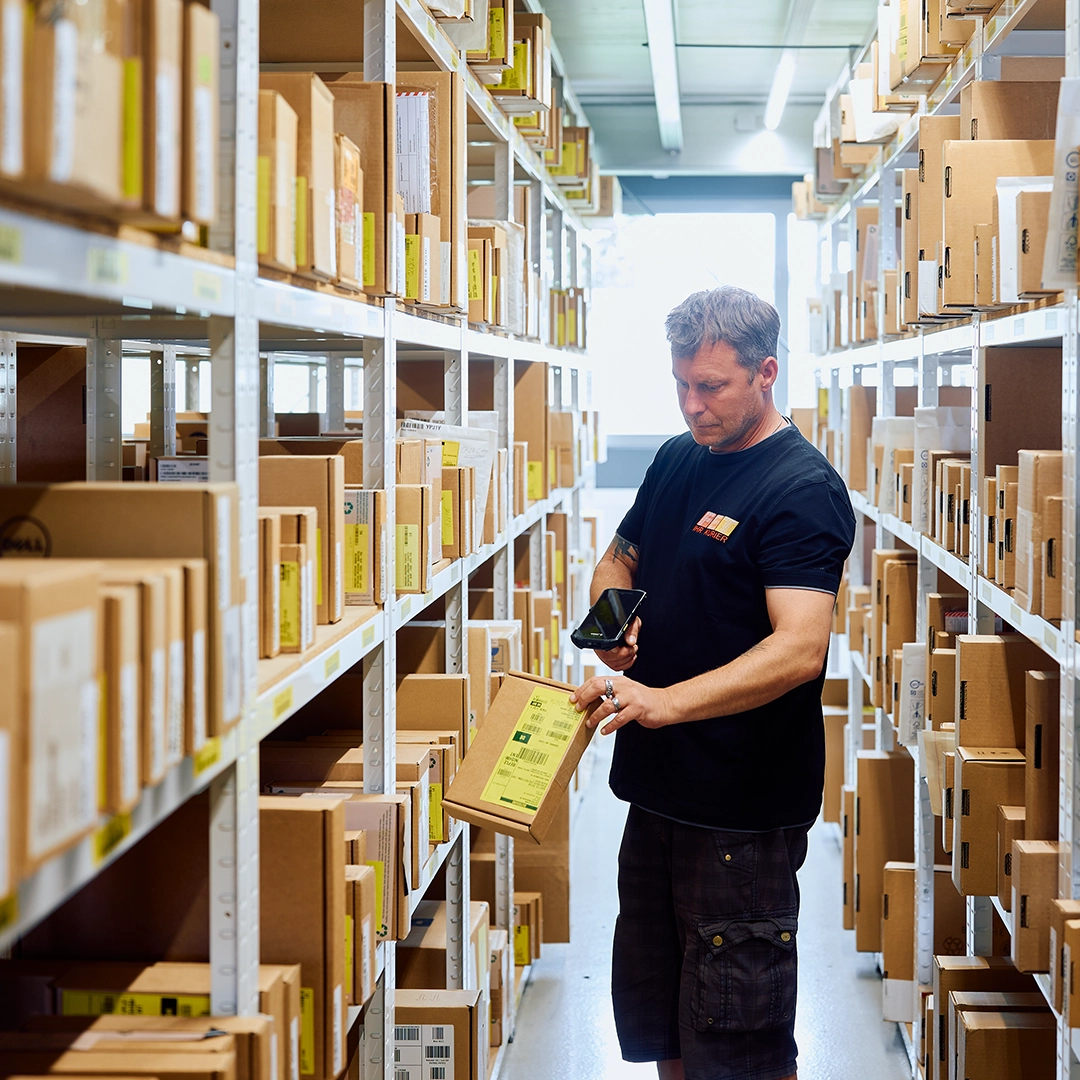 Ein FET Mitarbeiter prüft gelagerte Pakete in einem Regal – flexible Lagerung, Handverladung und High-Emergency-Lager mit europaweitem 24h-Service.